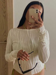 Textured white fitted long sleeve blouse with asymmetrical hem and ruched cuffs.