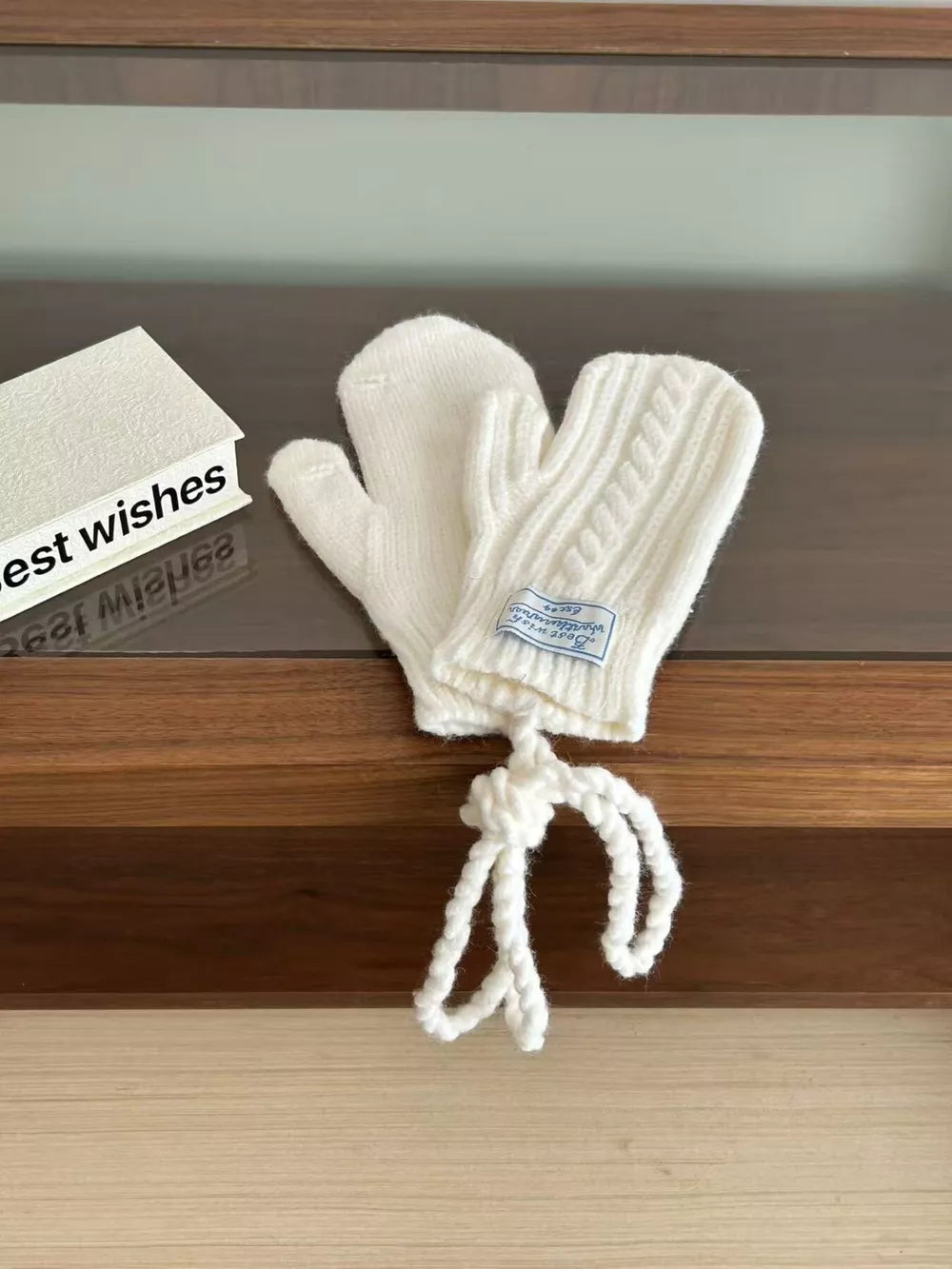 White cable knit acrylic mittens with braided detail and attached cord.