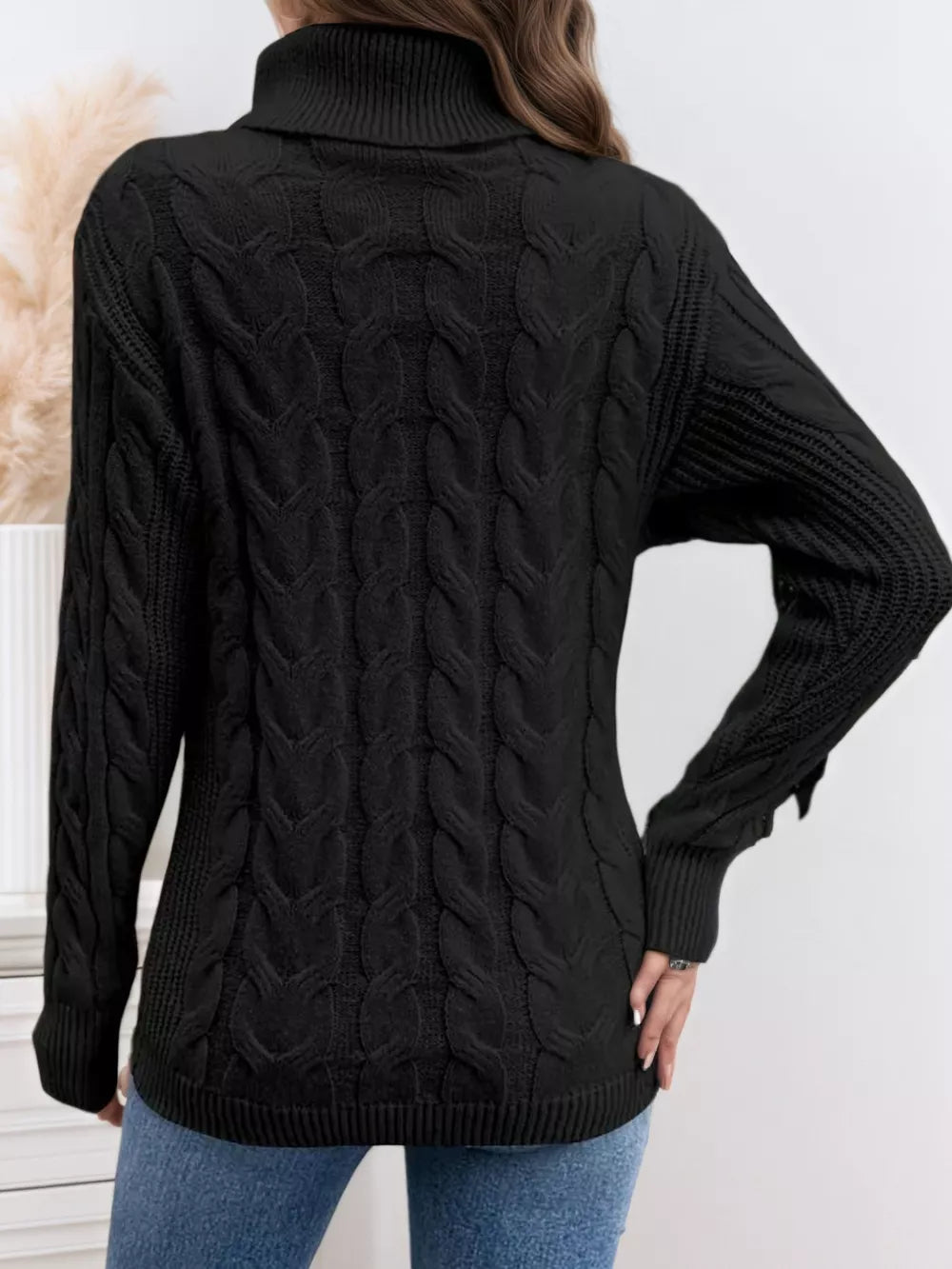 Black cable-knit turtleneck sweater with ribbed cuffs and hem.