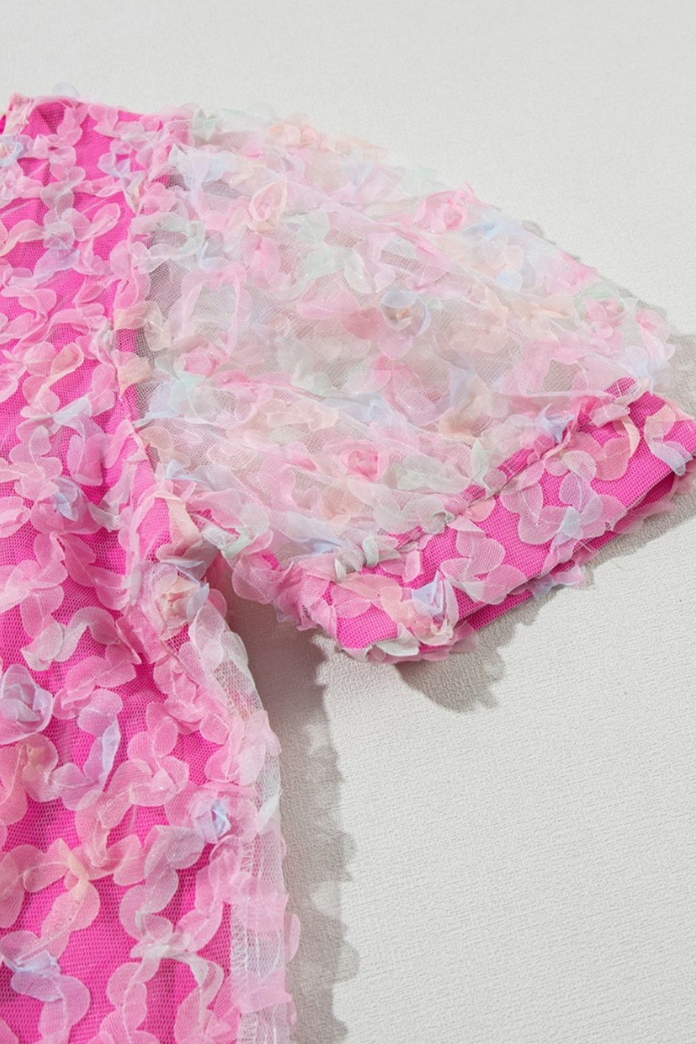Fuchsia pink blouse with floral appliqué mesh sleeves and textured fabric.