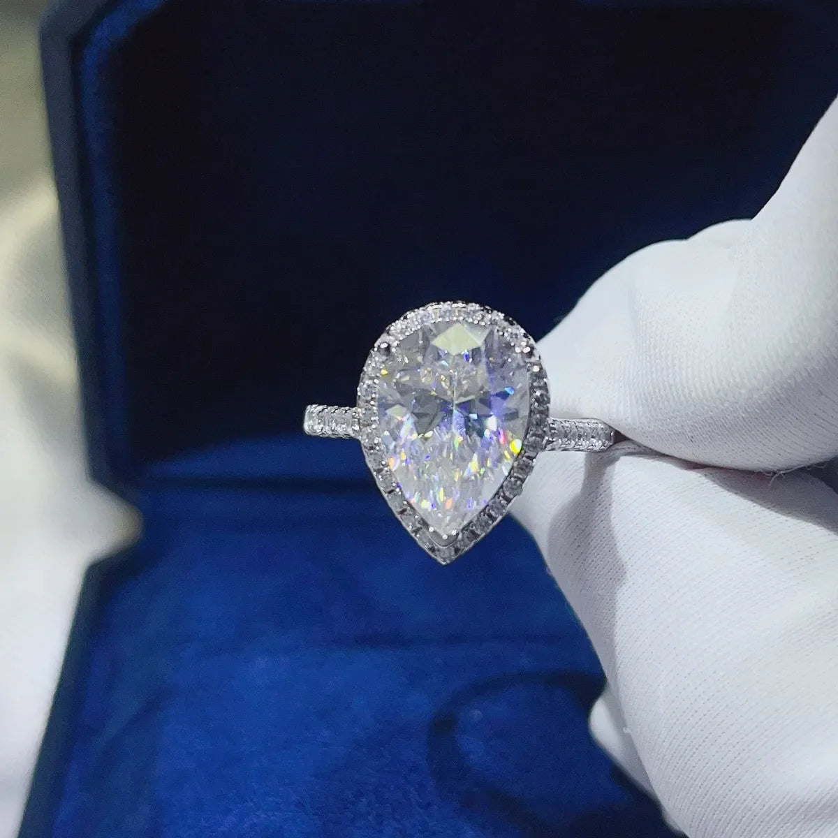 White pear-cut halo engagement ring with a diamond band.