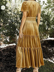 Velvet maxi dress in mustard yellow with ruched waist and tiered skirt.