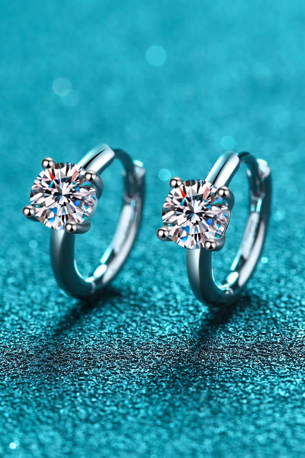 Silver solitaire halo hoop earrings with a sparkling round-cut center stone.