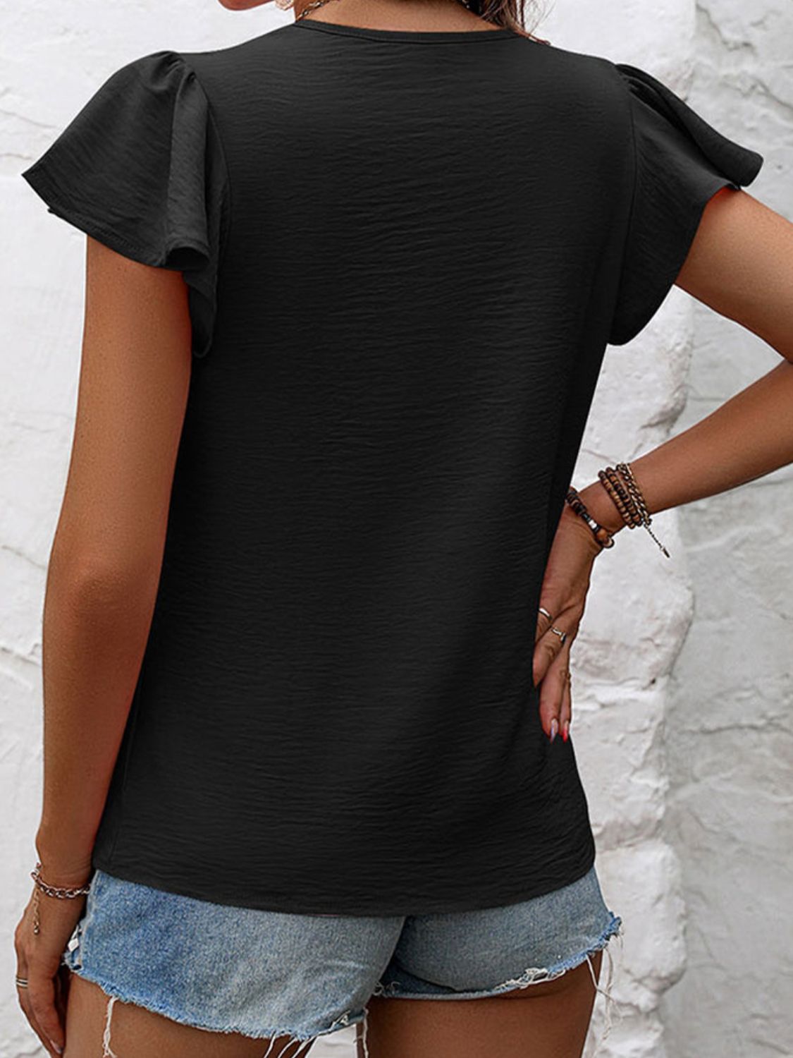 Black textured blouse with flutter sleeves and gathered detail.