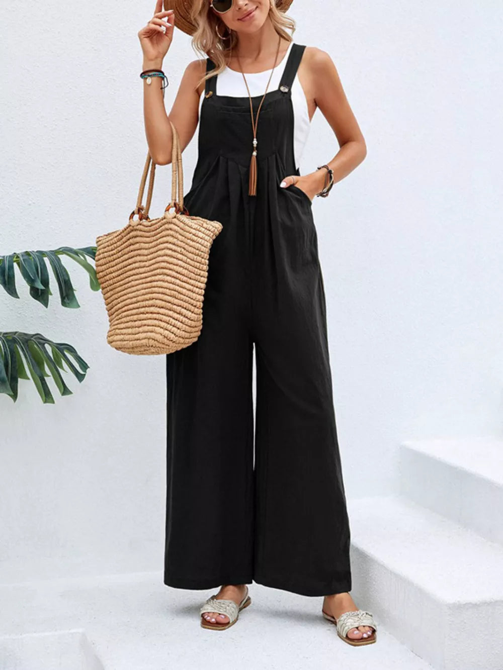 Black wide-leg romper with pockets, adjustable straps, and button details.