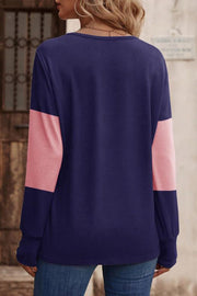 Navy and pink colorblock knit sweater with button cuffs.