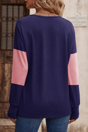 Navy and pink colorblock knit sweater with button cuffs.