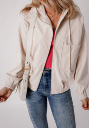 Cream corduroy bomber hoodie with drawstring hood, zip front, and chest pockets.