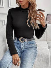 Black reversible cuff turtleneck top with long sleeves, styled with jeans and a belt.