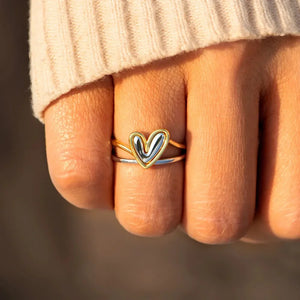 Two-tone gold heart outline ring stacked with a silver band.
