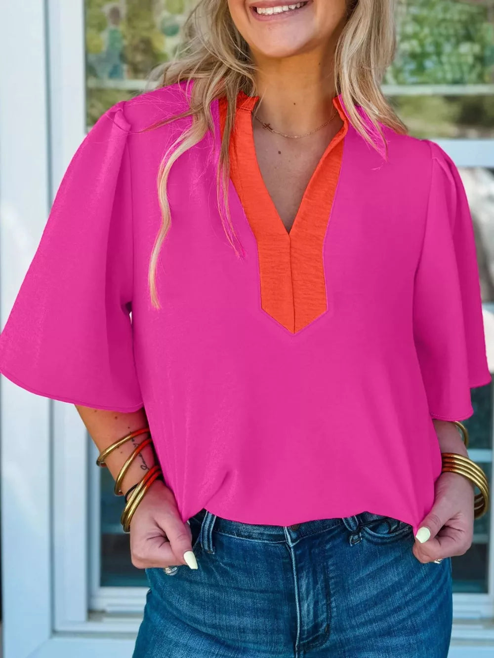 Textured pink blouse with orange V-neck trim and half sleeves.