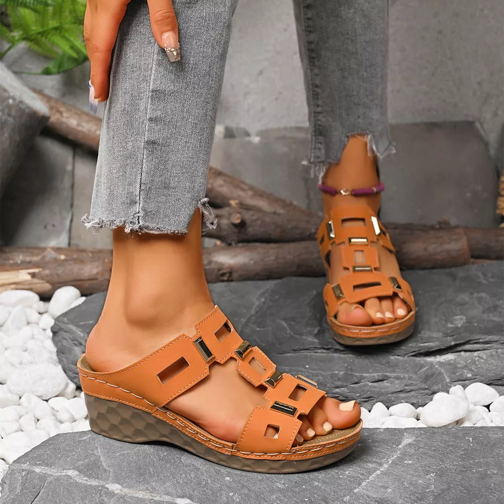 Brown open-toe wedge sandals with cutouts and gold accents.