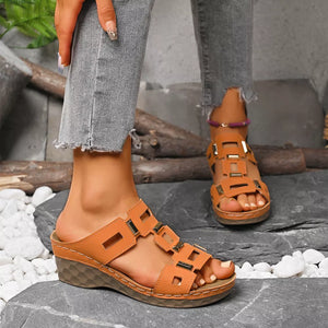 Brown open-toe wedge sandals with cutouts and gold accents.