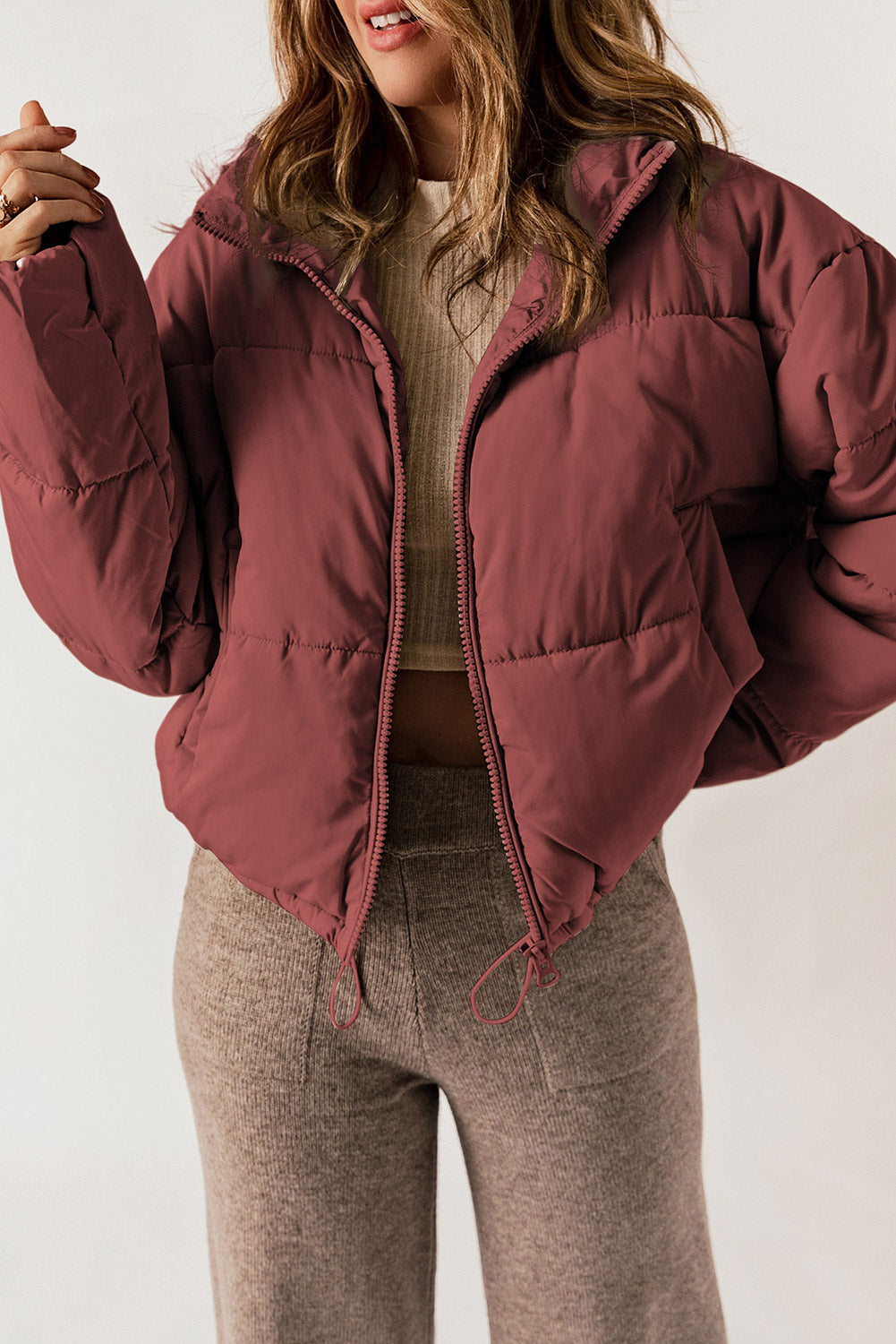 Cropped puffer jacket in brick red with a hooded collar and zip closure.