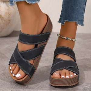 Black criss-cross open-toe platform sandals with white stitching and a chunky sole.