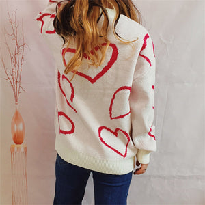 White knit sweater with red heart outline pattern, crew neck, long sleeves.