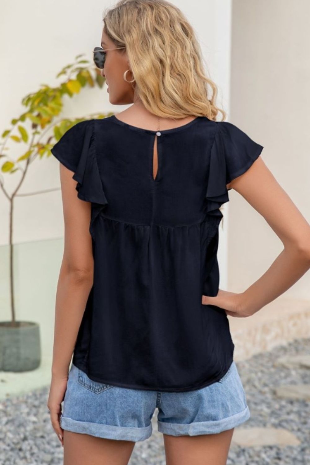 Navy ruffle sleeve blouse with keyhole back detail and embroidered yoke.