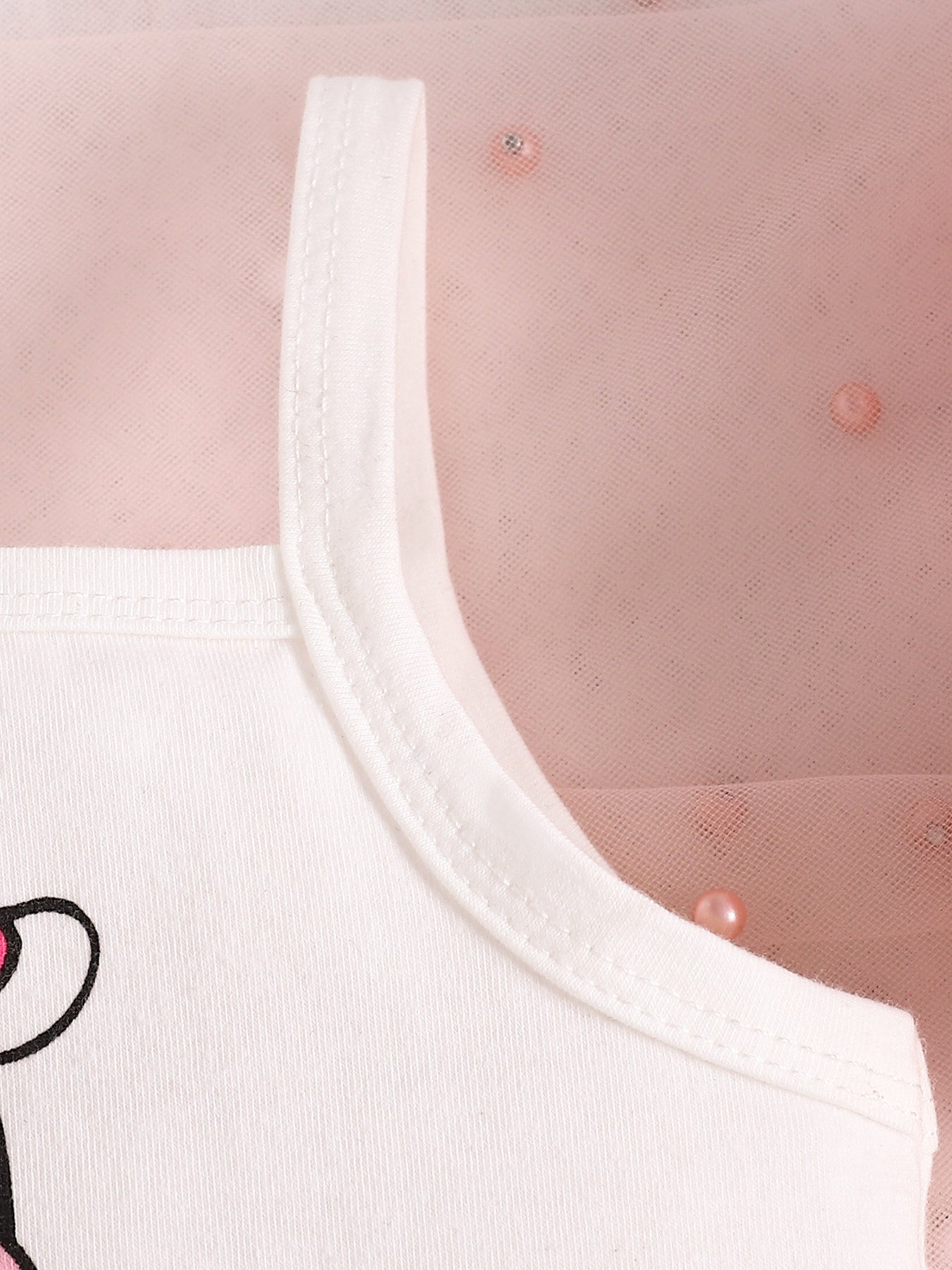 White cotton baby tank top with cow print detail and pink tulle overlay.