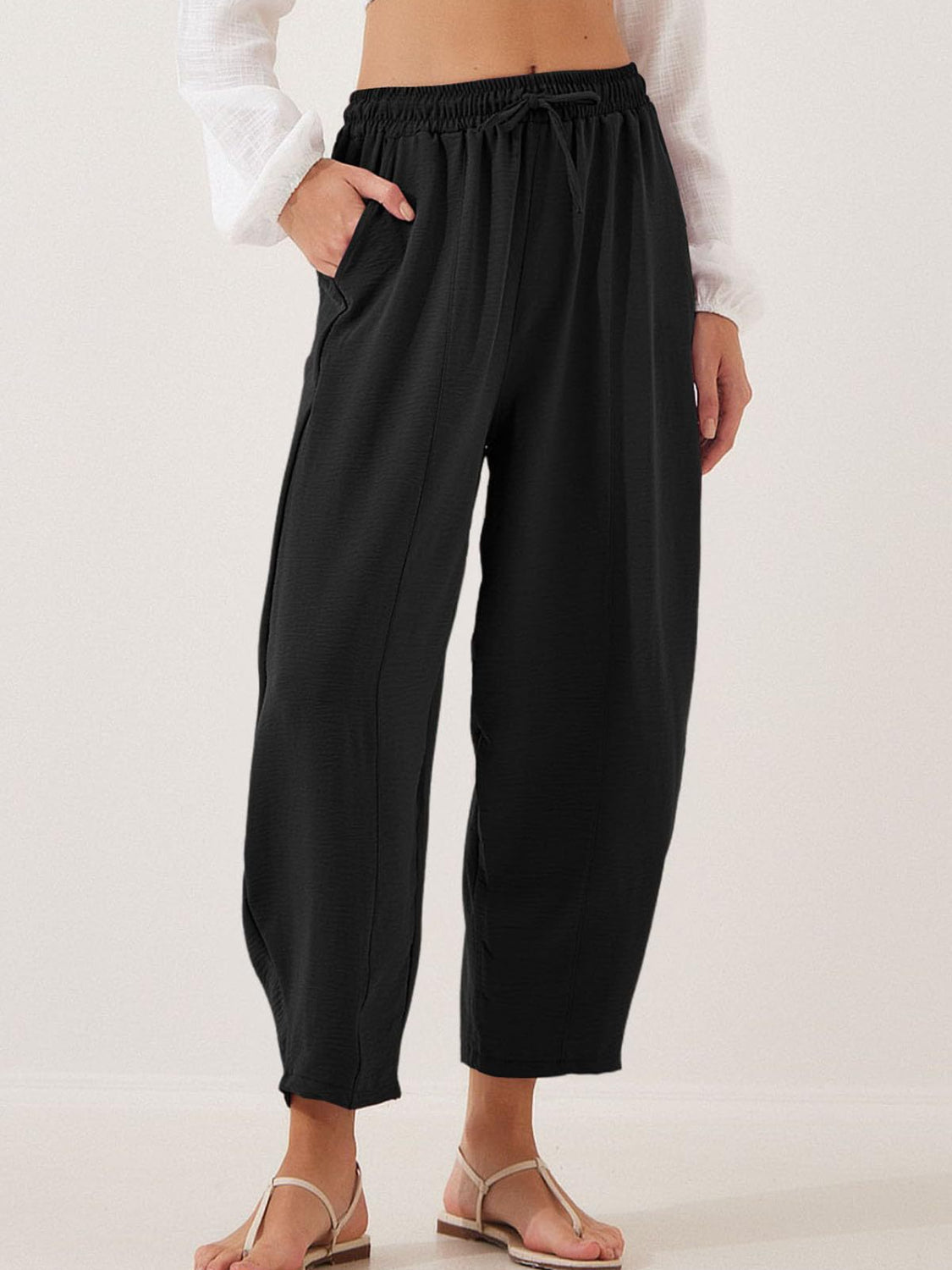 Black balloon trousers with drawstring waist and sculpted seamline detail.