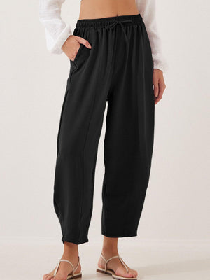 Black balloon trousers with drawstring waist and sculpted seamline detail.