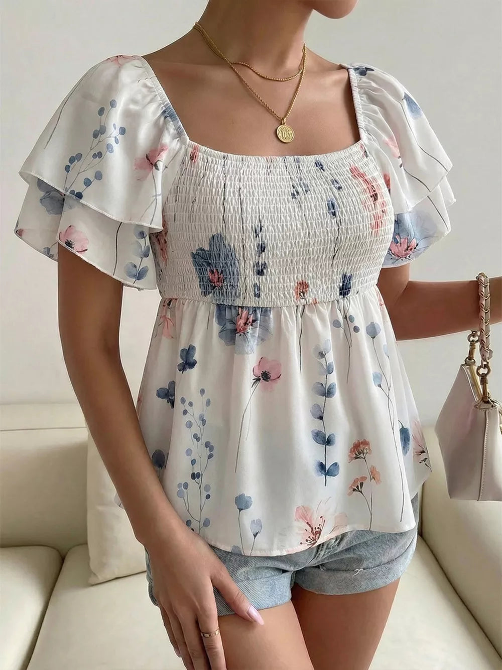 Smocked square neck blouse with flutter sleeves and a floral print.
