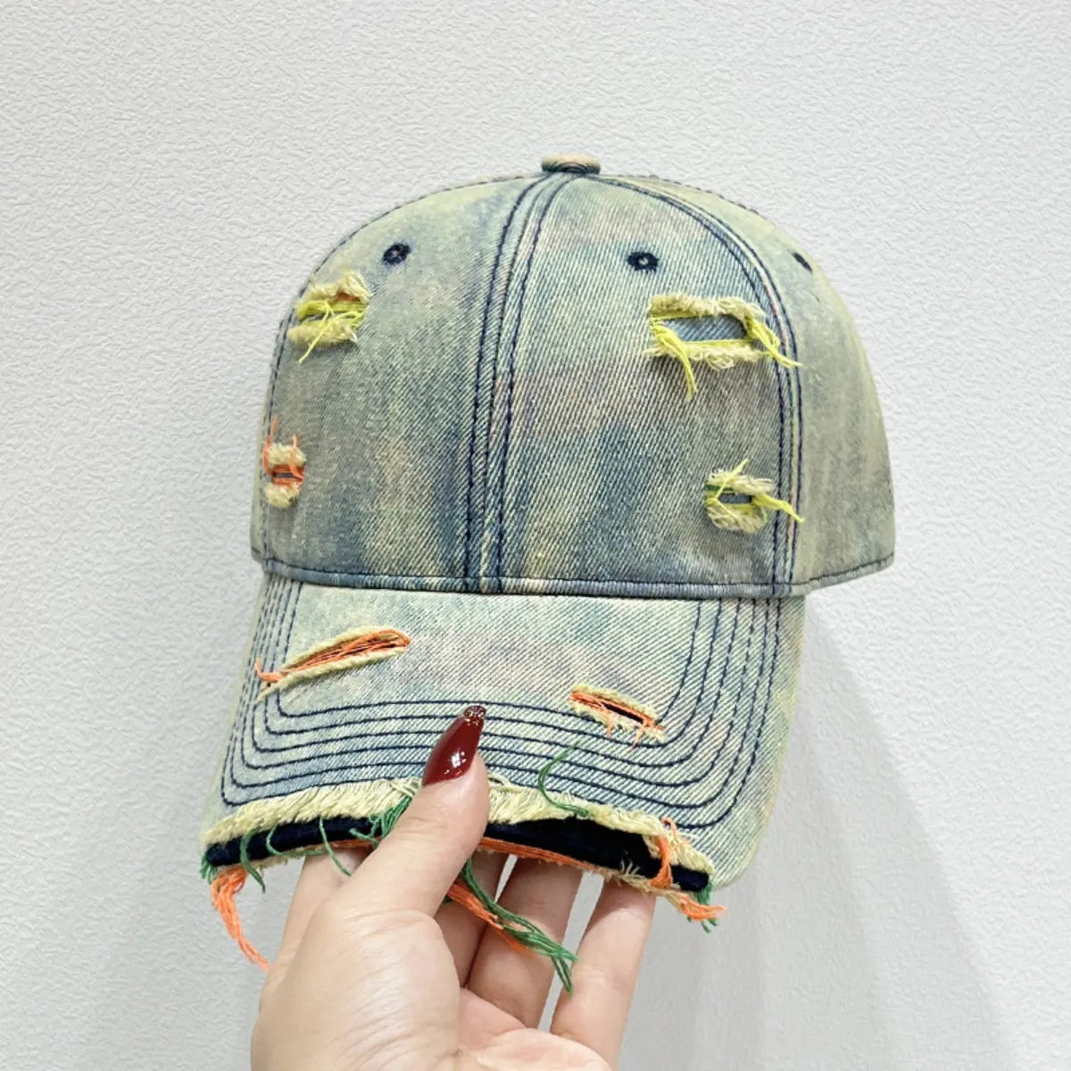Distressed light blue denim baseball cap with fraying and colorful threads.
