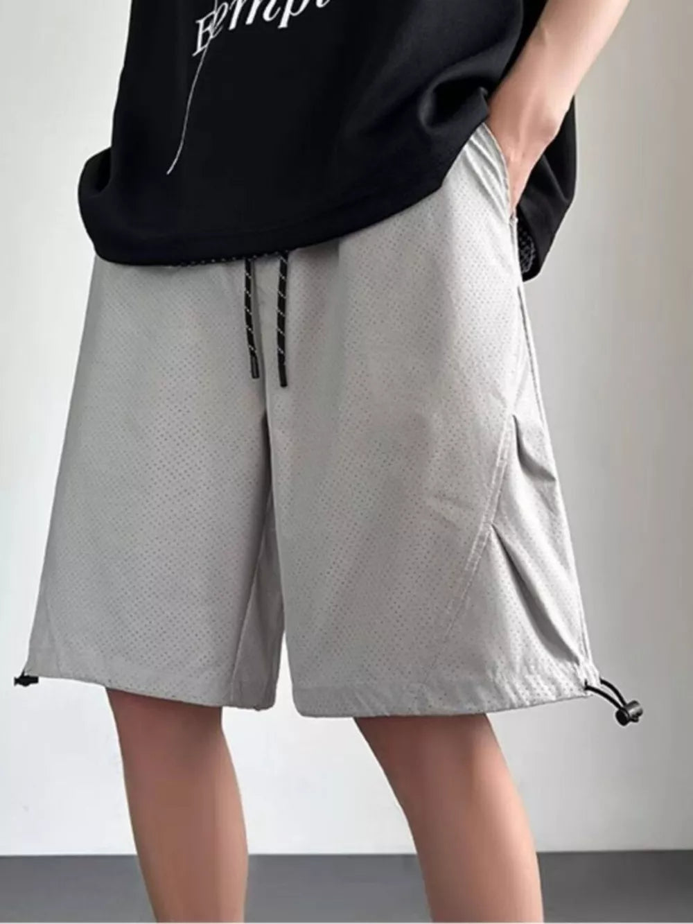 Gray perforated chino shorts with drawstring waist and adjustable hem.