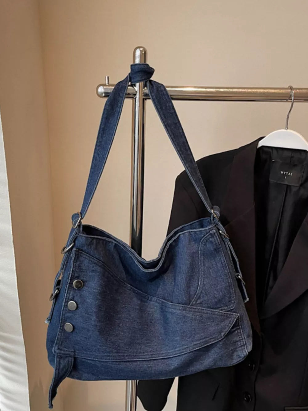 Relaxed denim crossbody bag with button accents and adjustable strap.