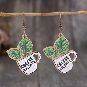 Coffee & Plants graphic drop earrings with green leaves and white cups.