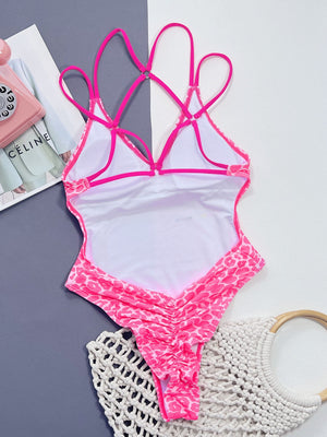 Hot pink leopard print one-piece swimsuit with strappy back and ruched detail.