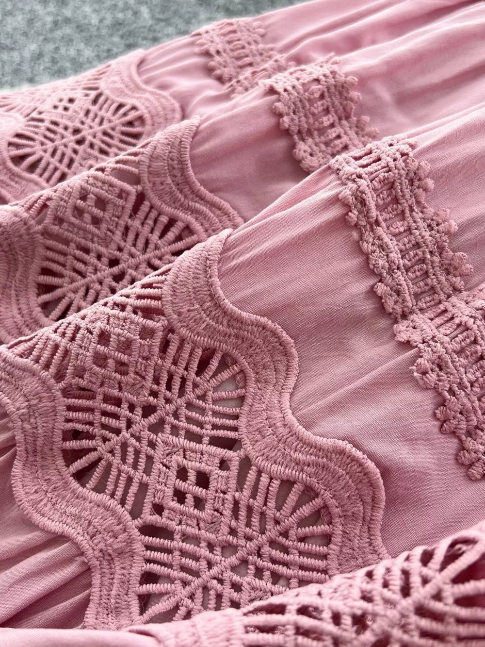 Pink tiered skirt with intricate lace embellishments and a drawstring detail.