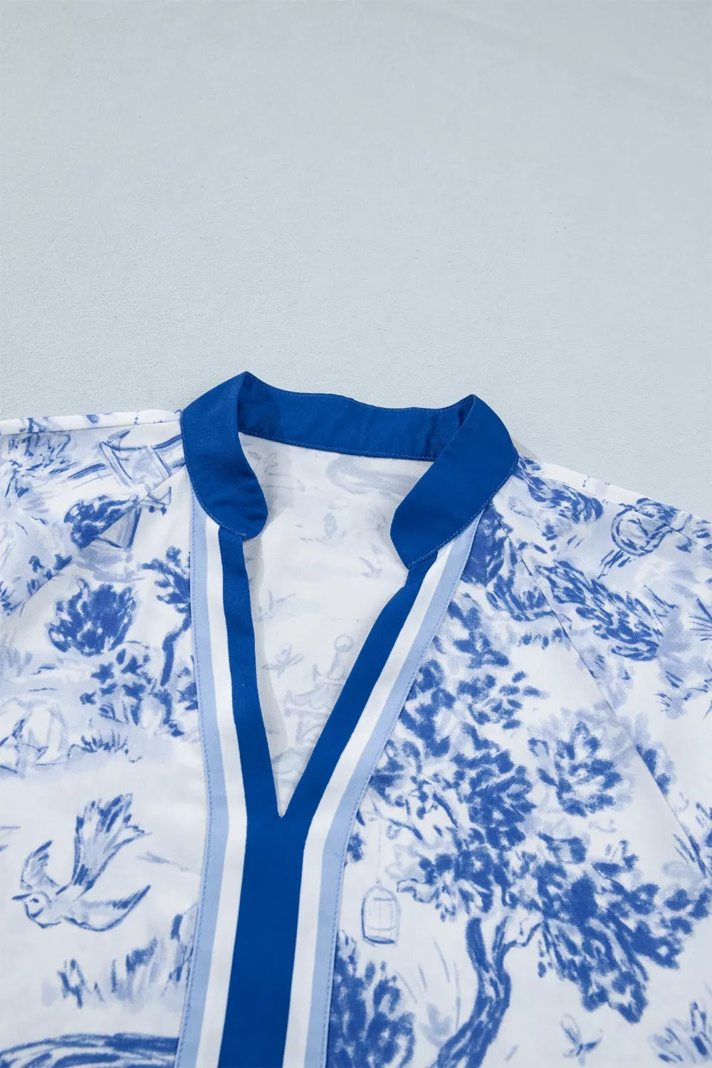 Women's blue and white toile print V-neck shirt with contrast trim.