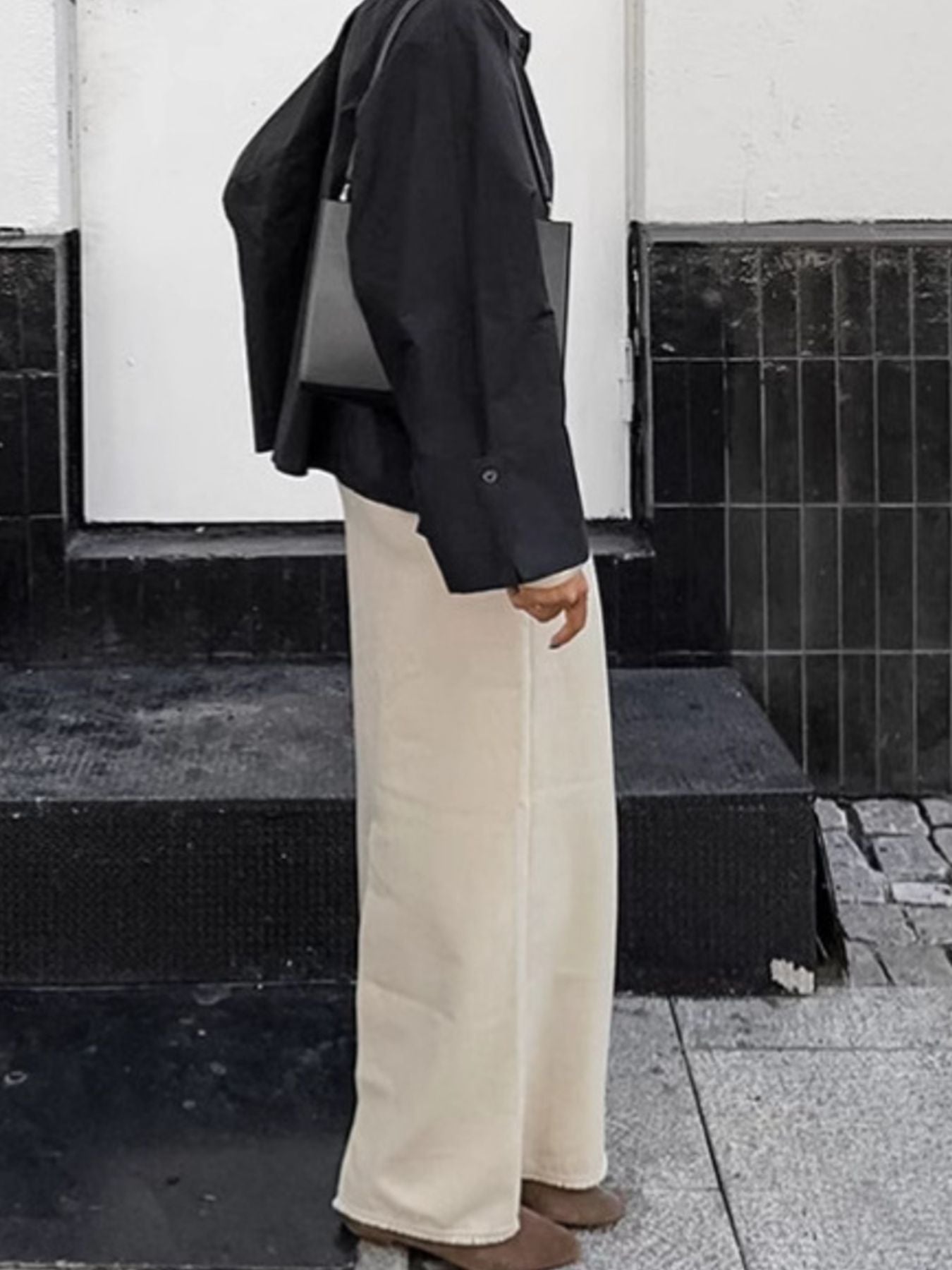 Chic cotton midi skirt with slit in beige, styled with a black jacket and bag.
