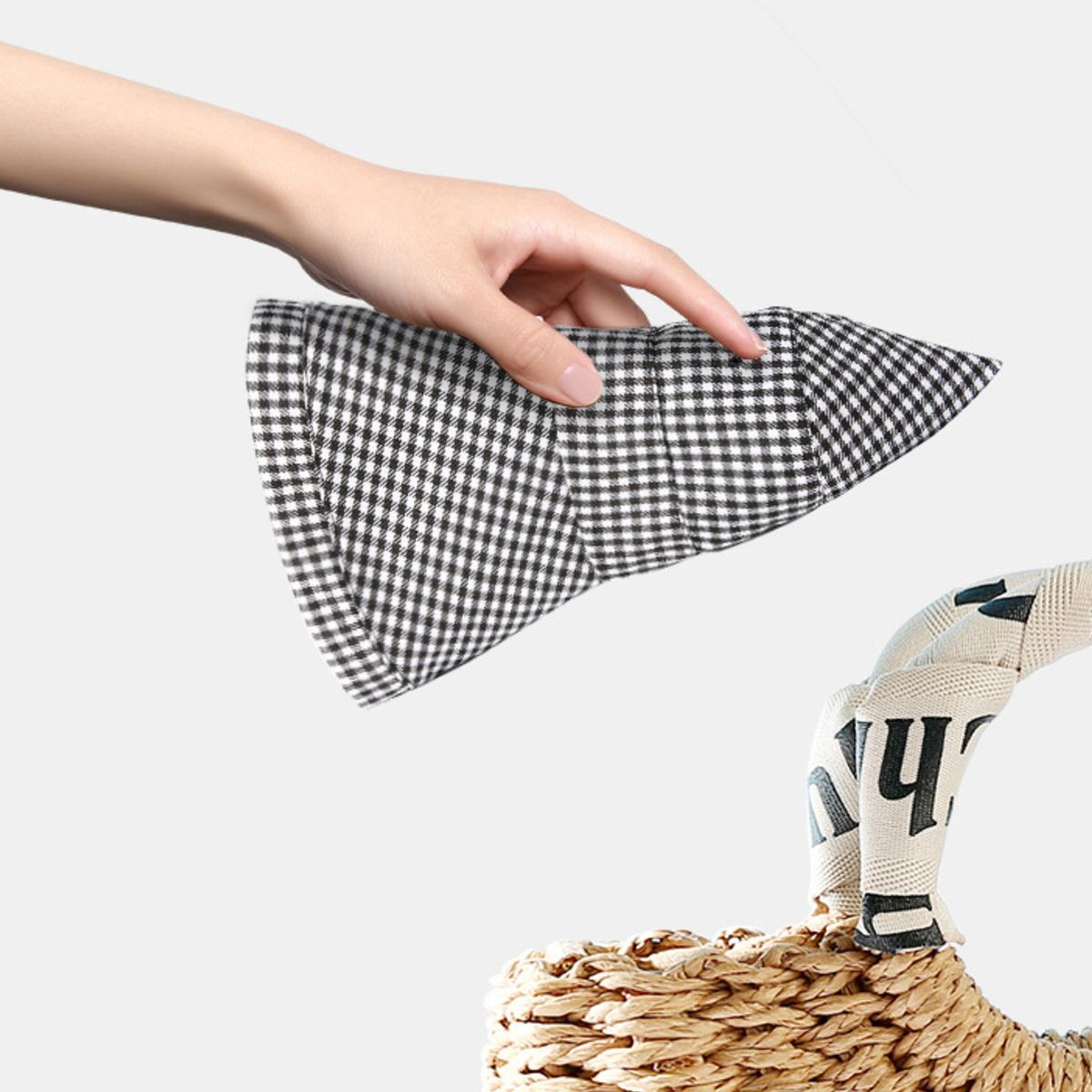 Gingham bucket hat in black and white checkered pattern, held by a hand.