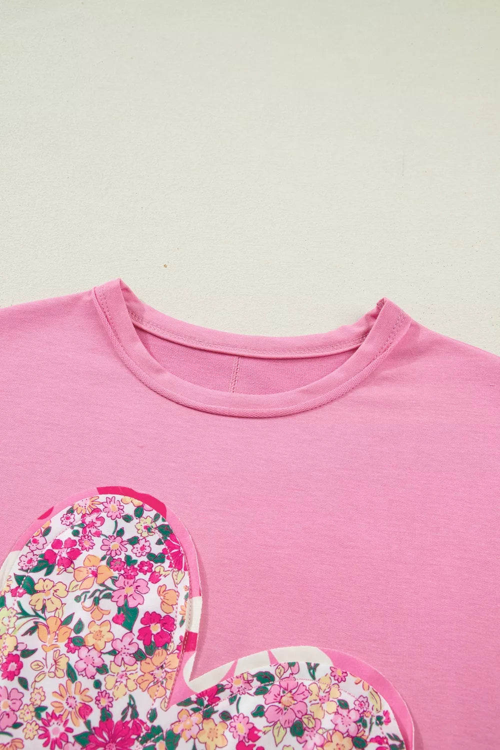 Pink cotton t-shirt with floral heart patch detail and crew neck.