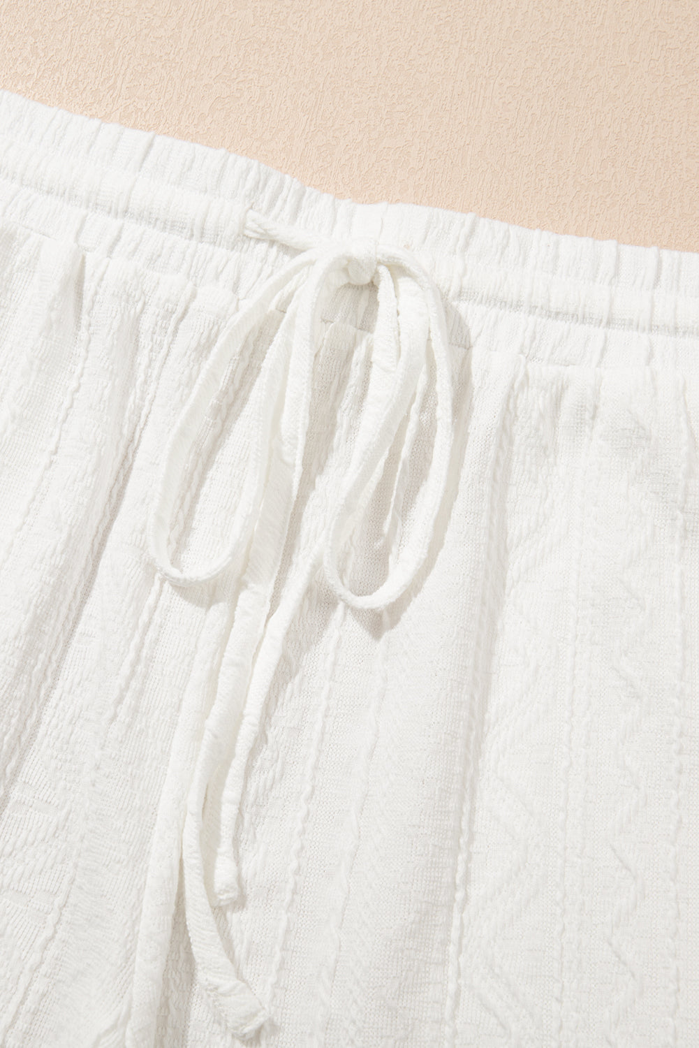 White textured knit drawstring shorts with a detailed pattern and tie waist.