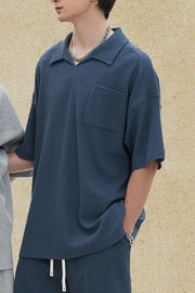 Boxy knit polo shirt in dusty blue with a patch pocket and spread collar.
