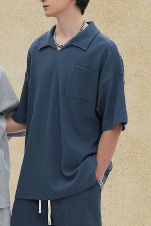 Boxy knit polo shirt in dusty blue with a patch pocket and spread collar.