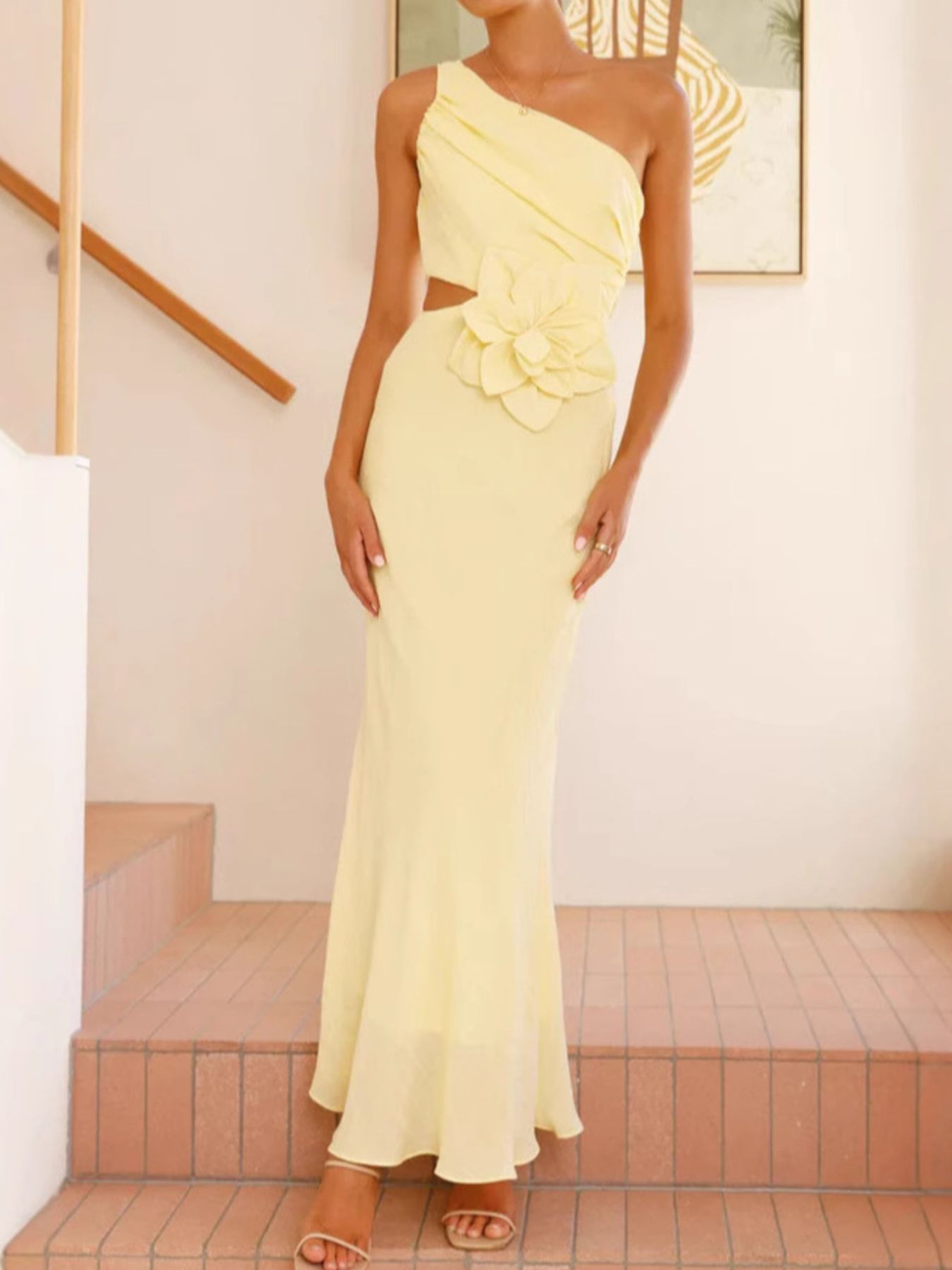 Yellow one-shoulder maxi dress with cutout and floral appliqué detail.