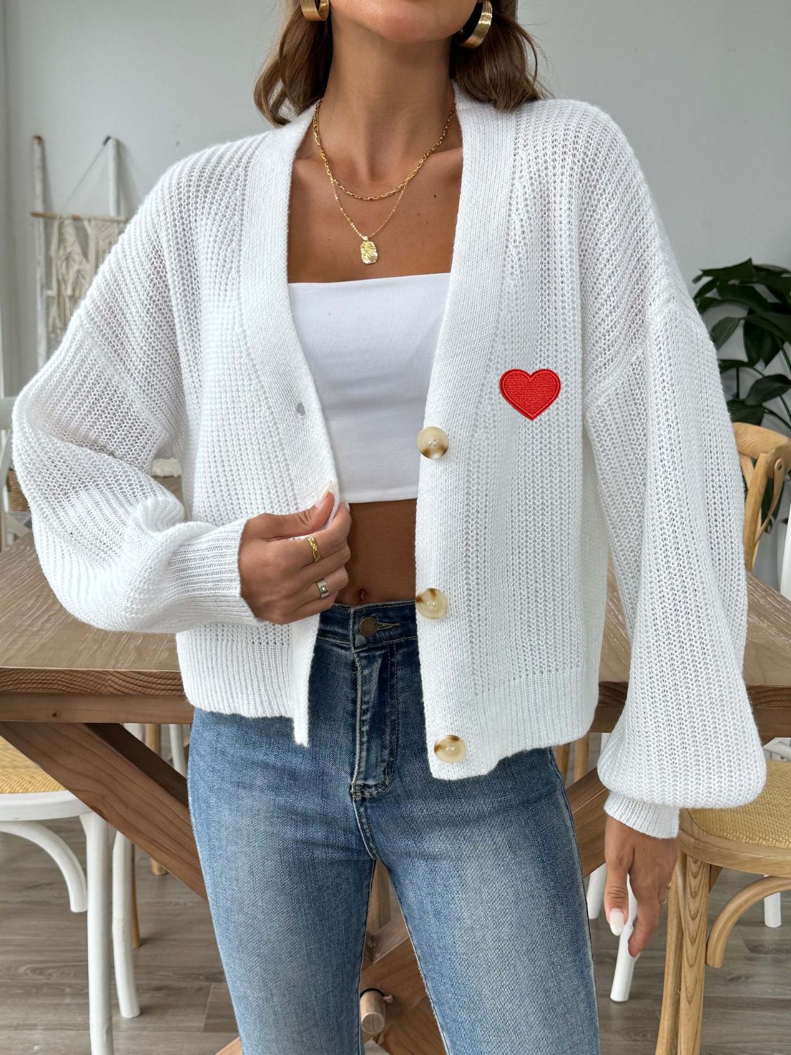 White knit cardigan with balloon sleeves and red heart appliqué, buttoned front.