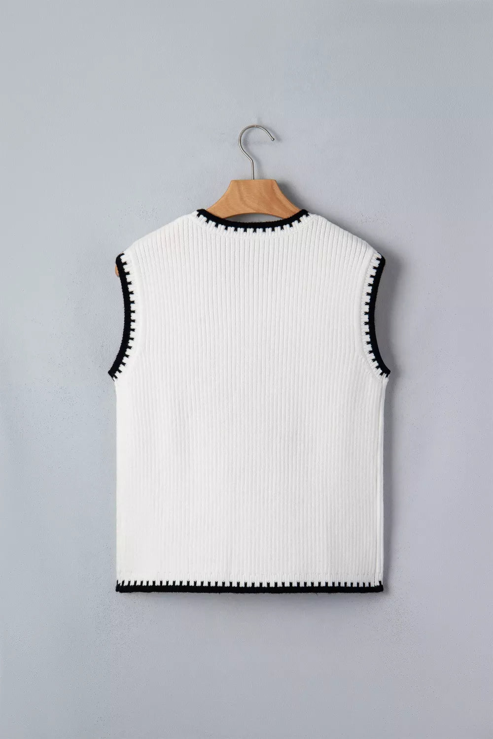 White ribbed knit sweater vest with contrast black trim and sleeveless design.