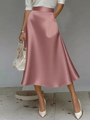Pink satin A-line midi skirt with pockets, flowing silhouette.