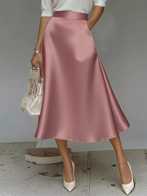 Pink satin A-line midi skirt with pockets, flowing silhouette.