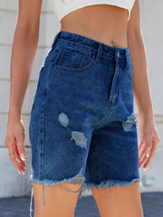 Distressed denim bermuda shorts in medium wash with frayed hem and rips.