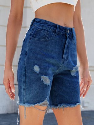 Distressed denim bermuda shorts in medium wash with frayed hem and rips.