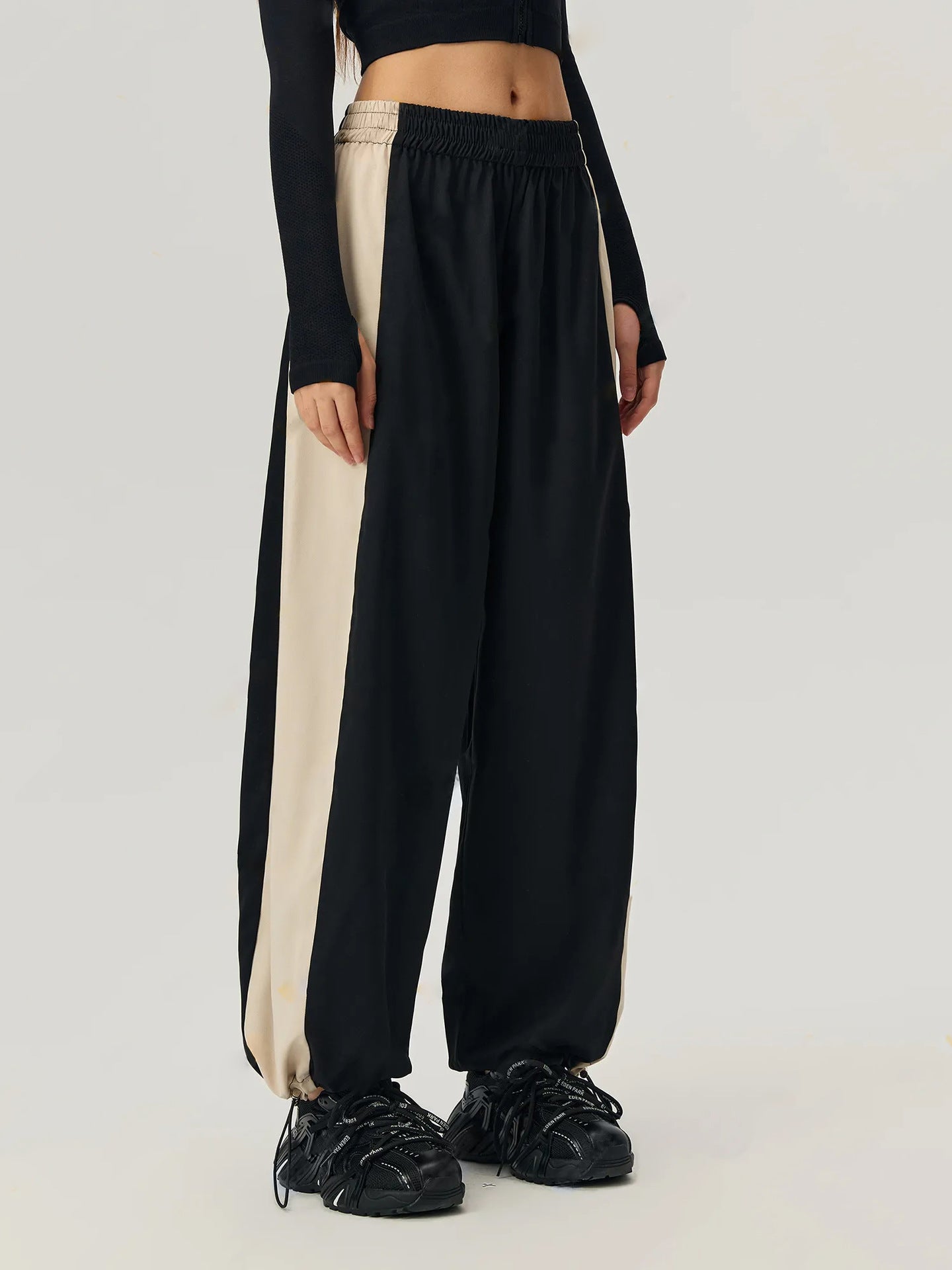 Panelled wide-leg track trousers in black with beige side stripe detail and elastic waistband.