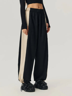 Panelled wide-leg track trousers in black with beige side stripe detail and elastic waistband.