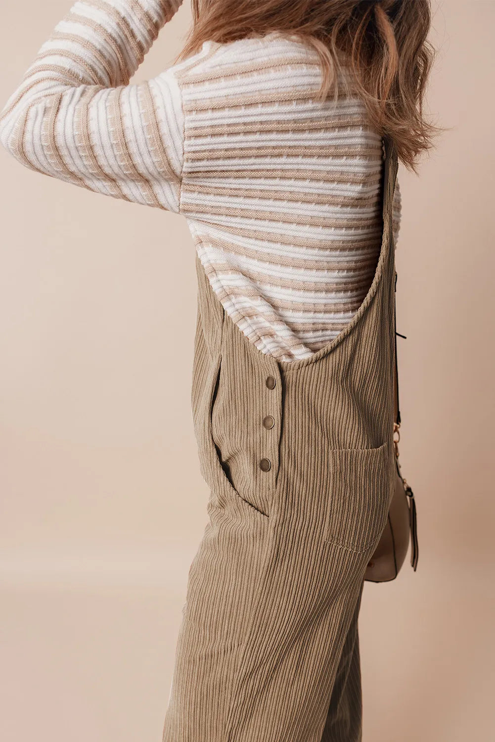 Camel corduroy wide-leg overalls with button detail and pockets, styled with a striped knit top.