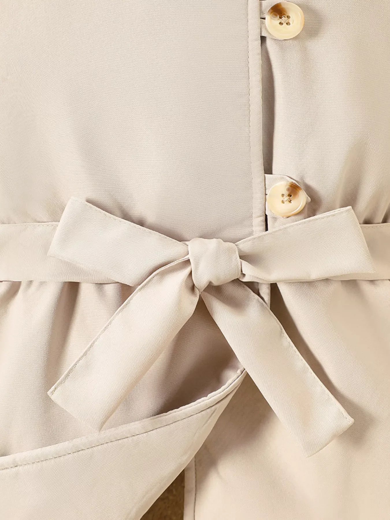 Apricot belted coat with bow detail and button closure.
