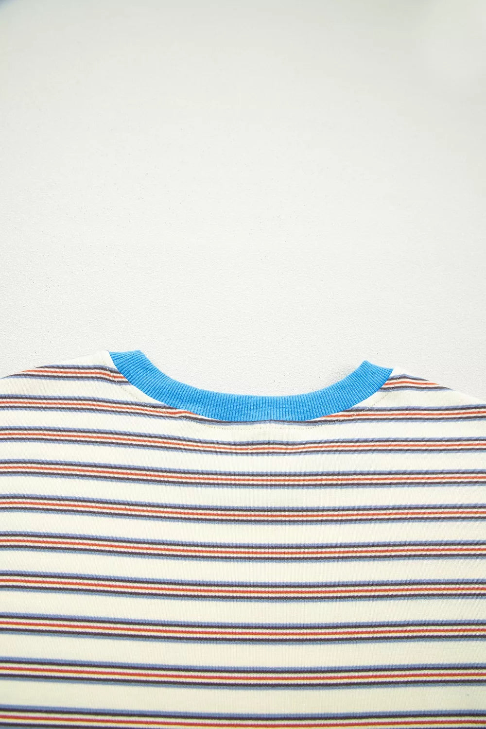 Casual striped mini dress with pockets, cream with blue, red, and navy stripes and a blue neckline.